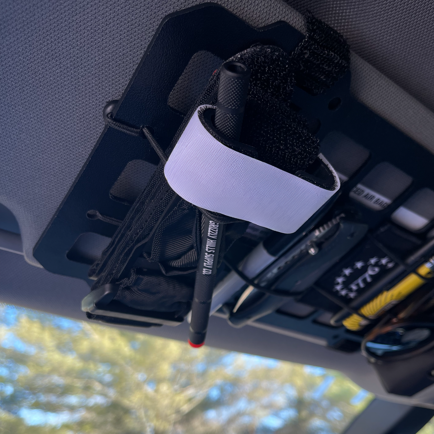 Photo of the tourniquet attached to the driver's side visor of a vehicle. Safety First!